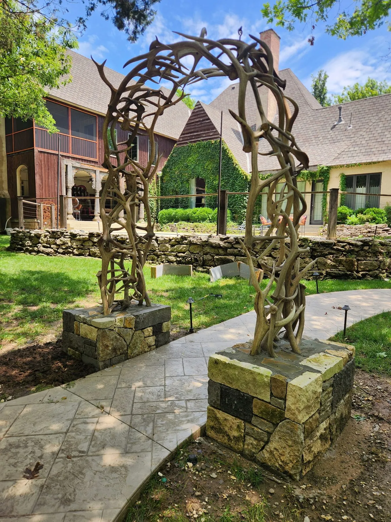 Real elk antler arch anchored over a path on stone columns with concrete-filled footings in Owasso