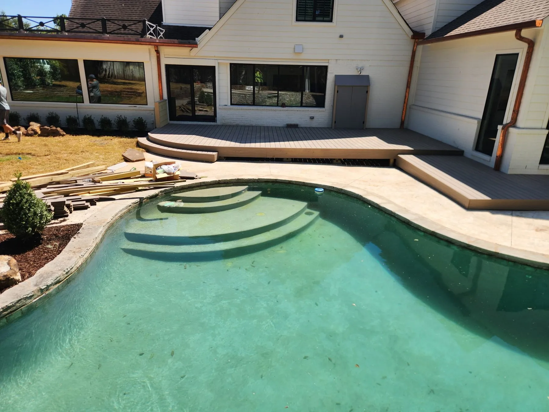 Backyard pool beside a two-level Trex composite deck with curved steps in Tulsa