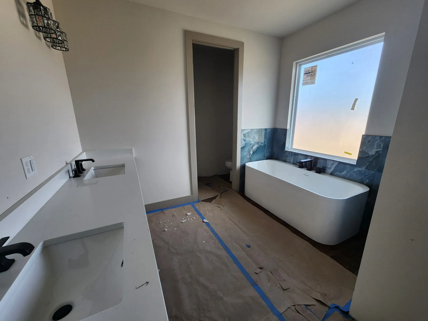 Freestanding soaking tub under a window with a blue tile accent wall in a Tulsa bathroom remodel