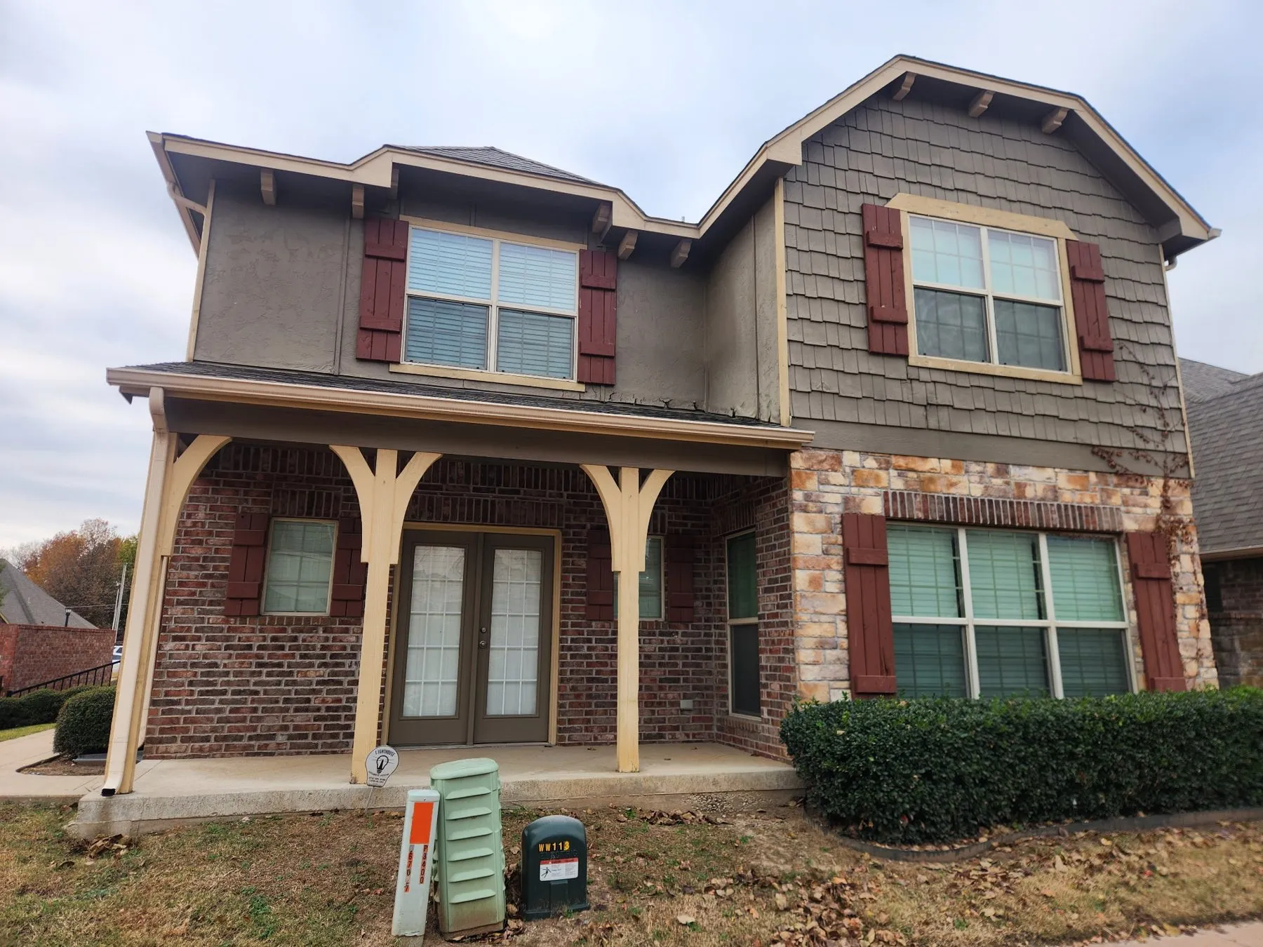 Gray siding, red shutters and stone porch on a two-story Owasso home after a full exterior repaint