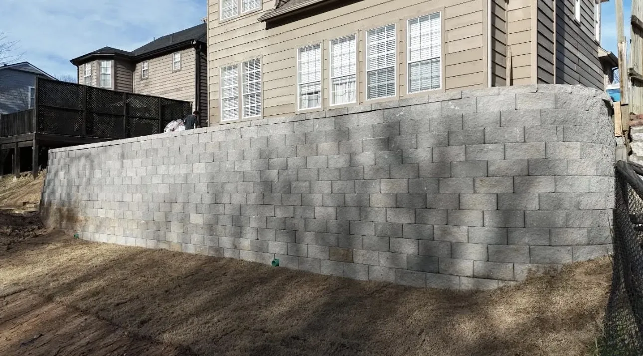 Finished engineered 11-foot block retaining wall with a French drain beside a Broken Arrow house