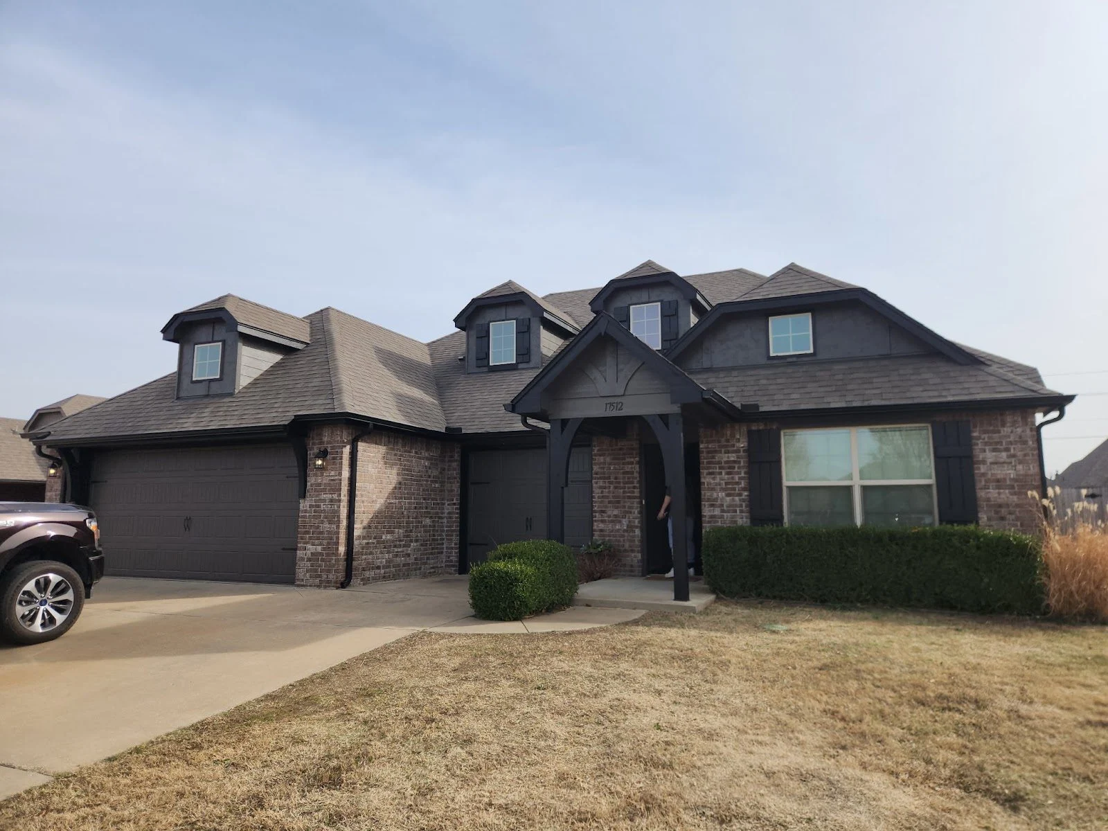 Brick home with dark trim and garage doors after a full exterior repaint in Broken Arrow
