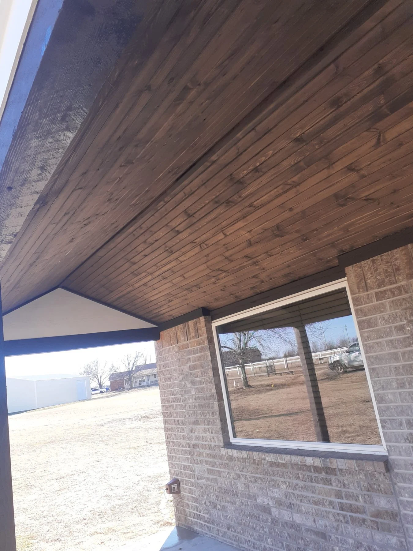 New stained wood soffit material on the porch ceiling of an Owasso home