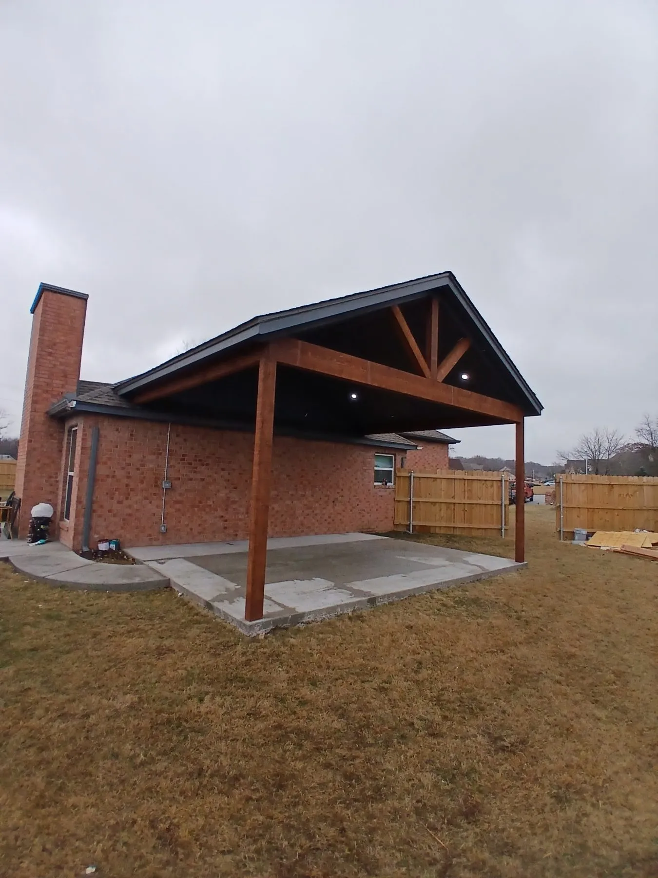 Concrete slab beneath the stained cedar posts and beams of an extended covered porch in Collinsville