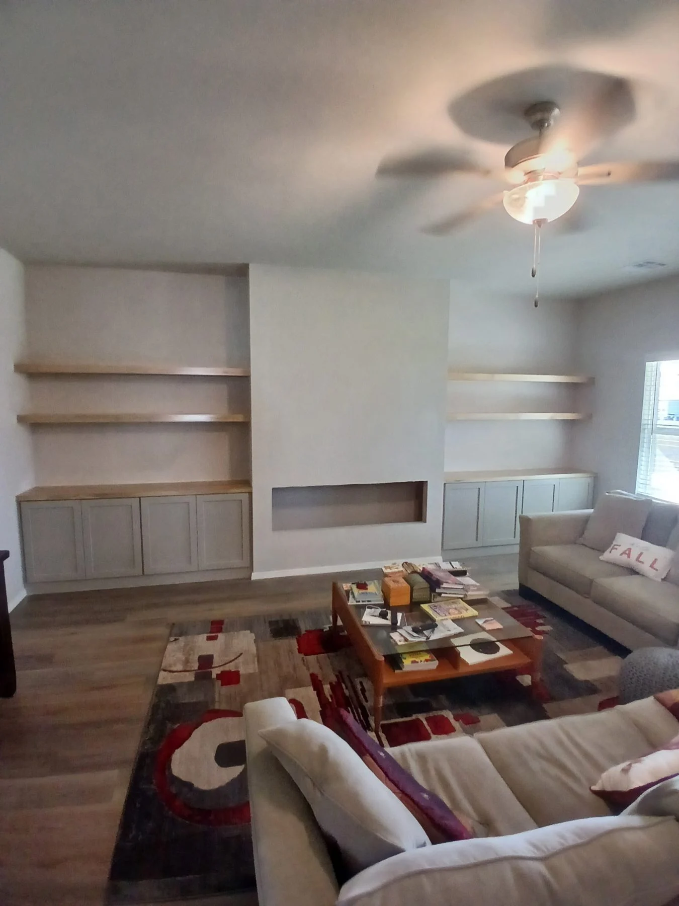 Framed fireplace bump-out with cabinets and floating shelves on both sides in a Bixby living room